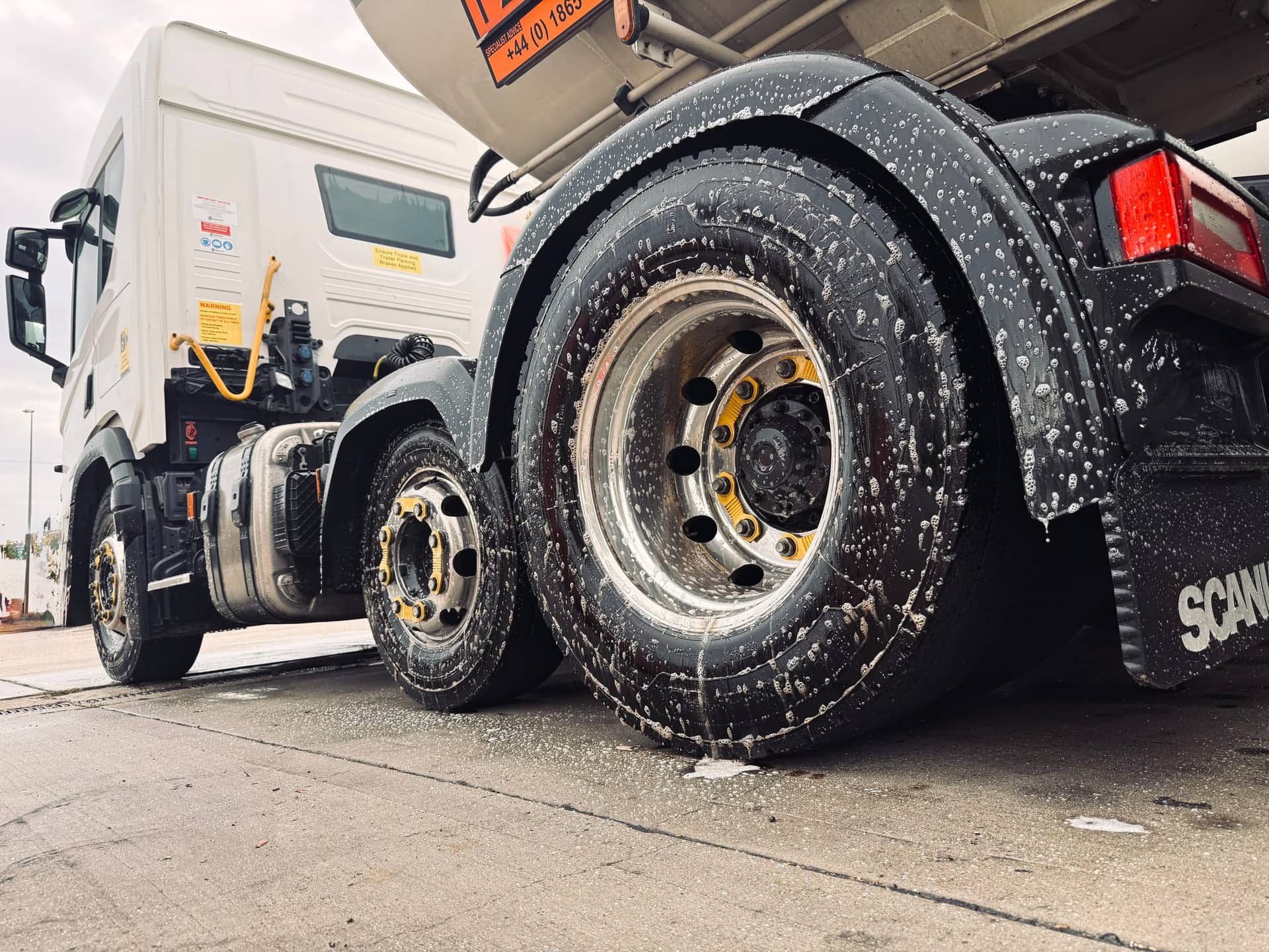 Foamed commercial tractor unit wheels during an on-site fleet wash